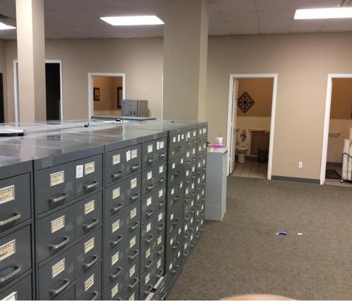 Camera angle aiming at 3 open bathrooms with filing cabinets on left side