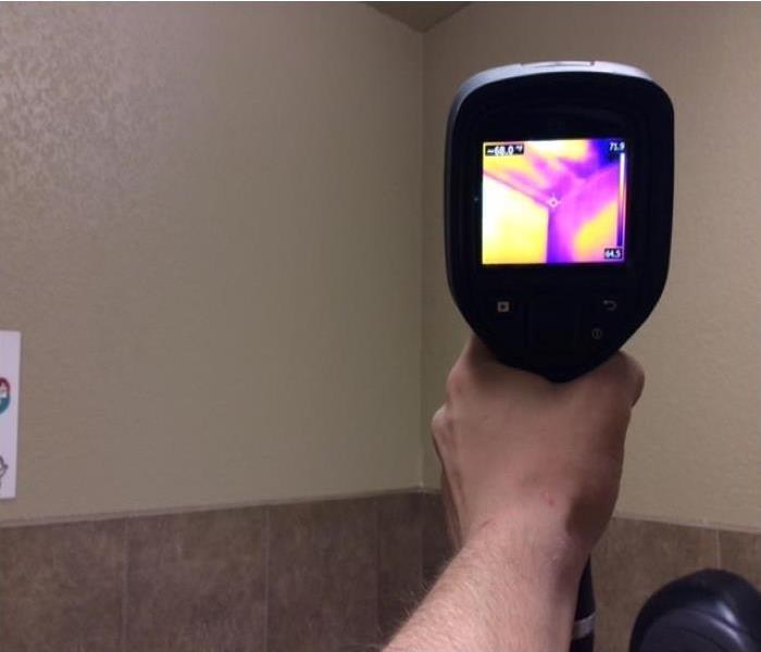 Our Crew Chief is using a thermal imaging camera to detect moisture that we can't see with the naked eye.